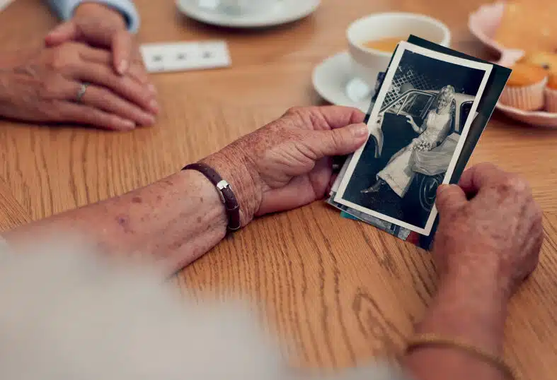 An old man holds a photograph to remember with the help of memory and dementia care.