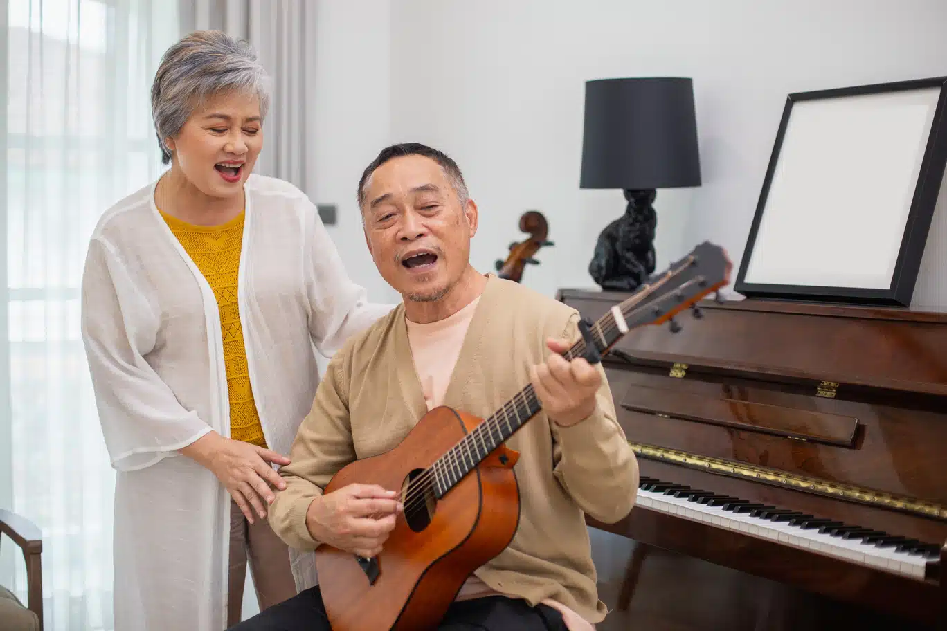 elderly couple having fun singing while playing guitar