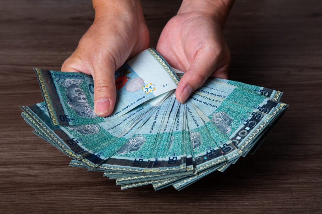 hands holding a stack of RM50 notes